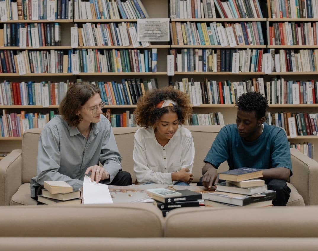 three university students studying in a library